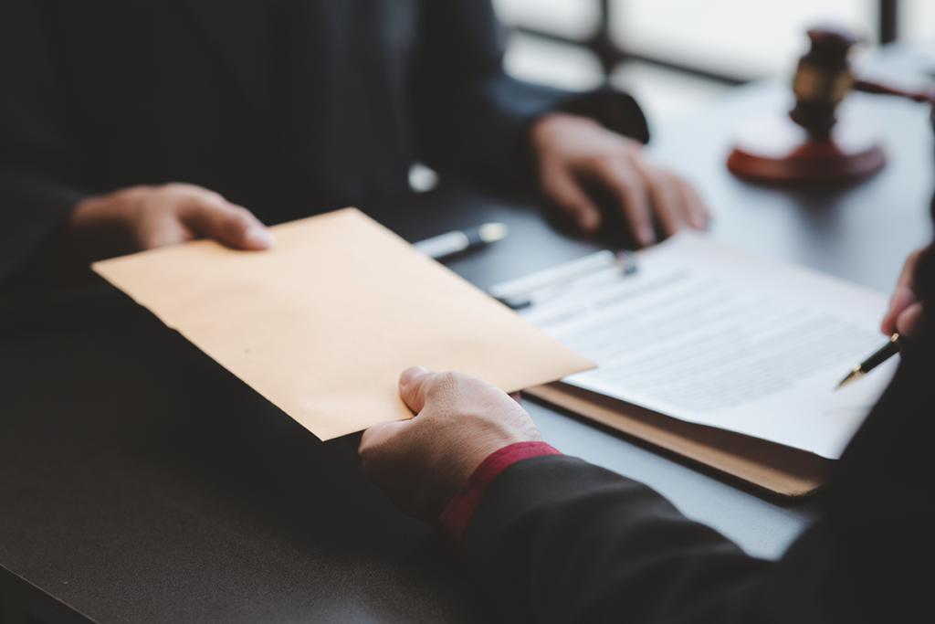 Expert Testimony. A person handing another person a packet of documents.