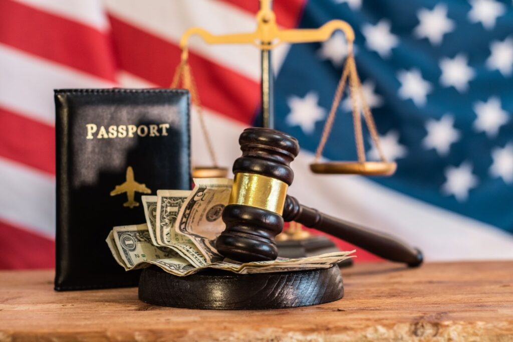 A judge’s gavel over money lies beside a passport with the American flag in the background, illustrating immigration court authority