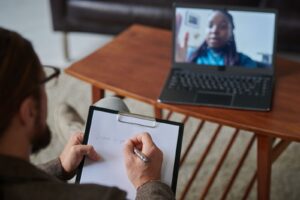 Licensed clinician taking notes while conducting a virtual psychological evaluation 