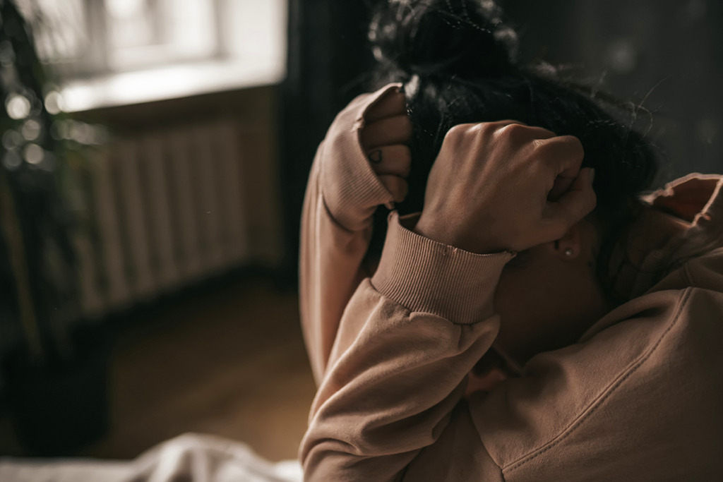 Asylum. A person with their head buried into their hands.